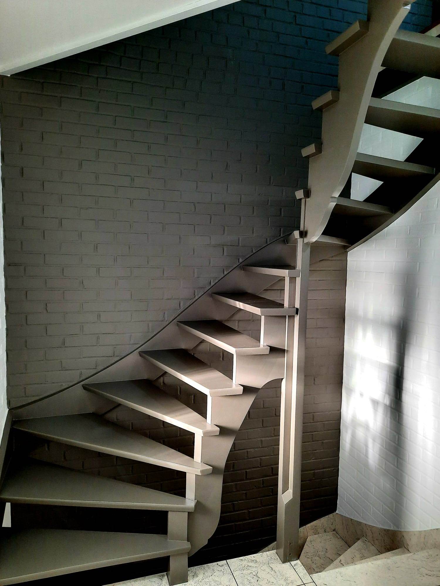 Escalier hélicoïdal et mur en briques repeints en gris